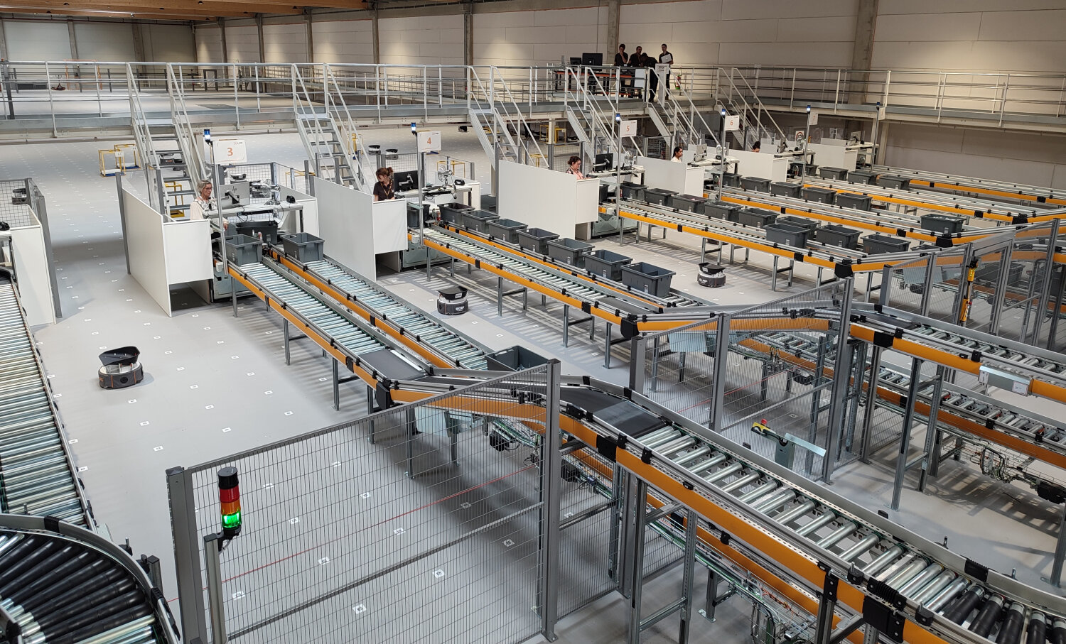 Des opérateurs se chargent de prendre les articles dans les bacs, avec un tri à gauche pour les commandes unitaires et à droite pour les commandes multi-articles. C’est là que le robot entre en scène. - © Républik Retail