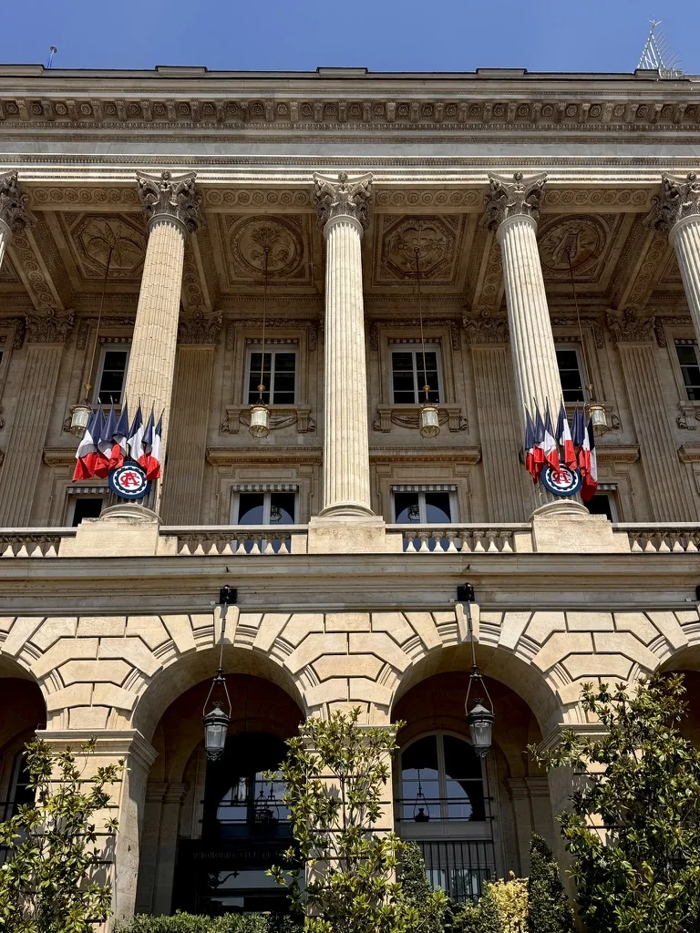 Façade à colonnes de l'Automobile Club de France, pavoisée de drapeaux tricolores.