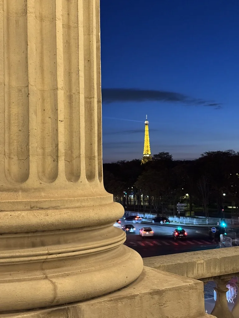 Vue depuis la colonnade du club : la tour Eiffel illuminée à la tombée du jour.