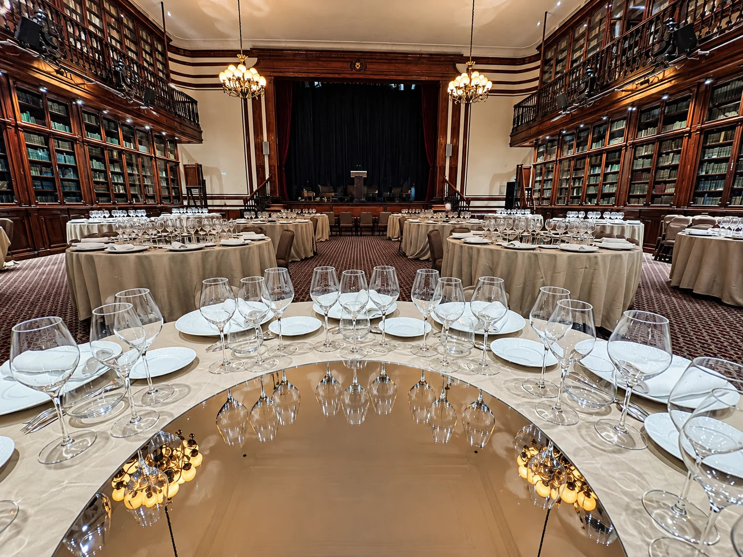La salle avant l'arrivée des convives : tables dressées, écran de scène et lustres allumés.